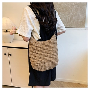 Detail of hand-woven hobo bag with textured straw pattern and leather shoulder strap