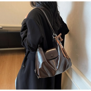 Détail du grand sac cabas en cuir ciré marron foncé avec pompon porté par un mannequin