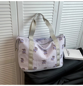 Detail of light purple quilted travel bag with cartoon bear pattern and fabric texture