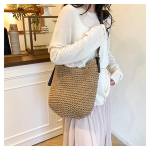 Detail of hand-woven straw shoulder bag featuring high-quality brown leather straps