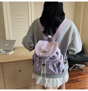 Detail of purple nylon backpack featuring adjustable drawstring and magnetic buckle closure