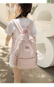 Lifestyle view of the light pink nylon backpack with side drawstring pocket and logo detail