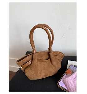 Detail view of brown suede tote bag featuring contrasting leather handles and textured finish