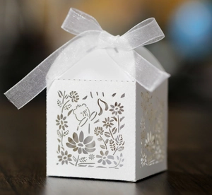 Detail of laser-cut white favor box with bear hollow design and white organza ribbon bow