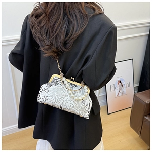 Detail of floral embroidery on a white shell bag with pearl handle and gold chain
