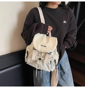 Detail of cream nylon backpack featuring drawstring closure and flap with logo detail