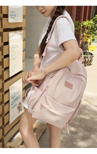 Outdoor side view of a minimalist light pink large-capacity backpack on model