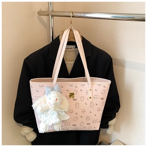 Pink leather tote with bear patterns and a plush bunny charm against a black blazer