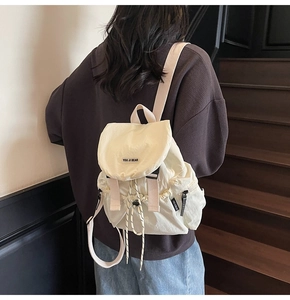 Detail of off-white nylon backpack with drawstring closure and You Ji Bear label