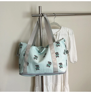 Detail of mint green quilted tote with bear prints and bottom zipper compartment