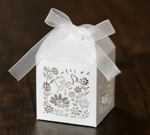 Macro view of white hollowed-out paper gift box with delicate laser-cut flower patterns
