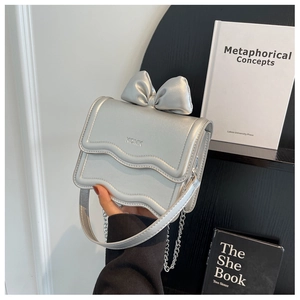 Detail of silver metallic crossbody bag featuring a wavy flap and 3D bow decoration
