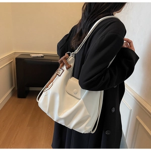 Detail of white pleated shoulder bag with brown T-shaped leather charm and thin strap