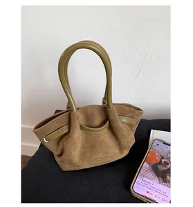 Detail of vintage suede tote bag showing brown matte finish and green leather handles