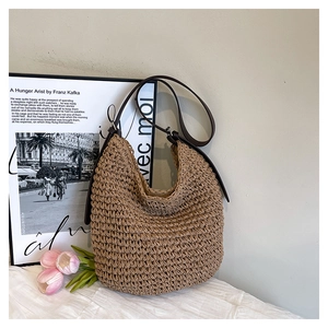 Detail of hand-woven straw shoulder bag with adjustable brown leather strap and metal buckle