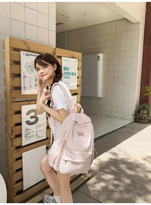 Outdoor lifestyle shot of a light pink casual backpack with multiple compartments for students