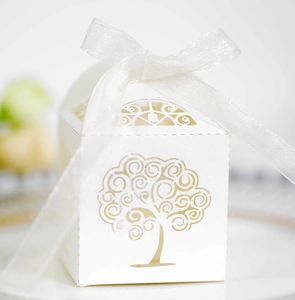 Macro shot of laser-cut tree of life pattern on white wedding favor candy box with ribbon