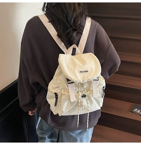 Detail of off-white nylon backpack with drawstring closure and brand logo on the back