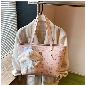 Pink tote bag with bear print featuring a plush bunny charm and golden logo plaque detail