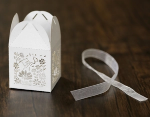 Detailed laser-cut floral pattern on a white pearlescent paper candy box with ribbon