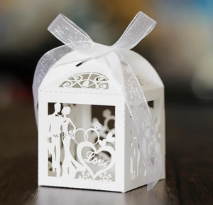 Close-up of white laser-cut wedding favor box with Love text and bride silhouette