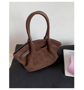 Close-up of dark brown suede tote bag with textured surface and smooth leather handles