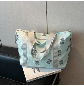 Close-up of mint green bubble fabric travel bag with cartoon bear patterns on a sofa