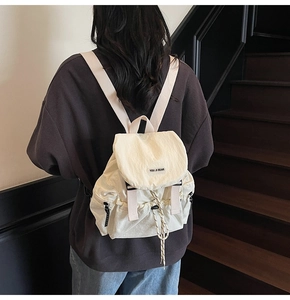 Detail of cream nylon backpack with flap drawstring closure and YOU JI BEAR logo branding