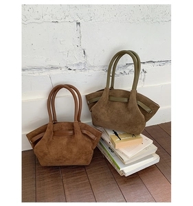 Detail view of brown and olive green suede tote bags on a rustic wood floor