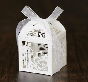 Close-up of laser-cut white wedding favor box with Love text and bride groom silhouette