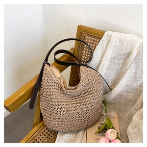Detail of straw woven hobo bag with brown leather strap on a vintage chair