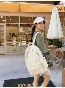 Detail of minimalist cream canvas backpack featuring large front pocket and side drawstring