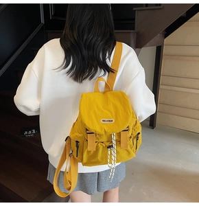 Close-up of lightweight yellow nylon backpack featuring drawstring closure and side pockets