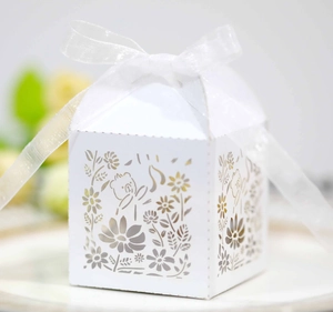 Detail of laser-cut white bear paper favor box with a delicate white silk ribbon bow