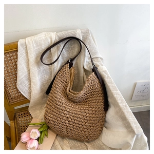 Detailed close-up of natural straw weave and dark brown leather strap on hobo shoulder bag