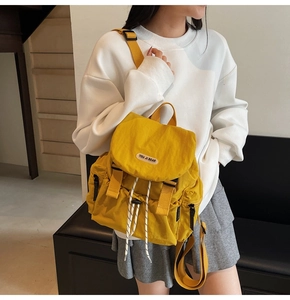 Close-up of bright yellow nylon backpack with flap drawstring closure and brand label