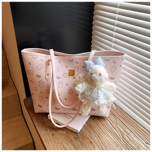 Pink leather tote bag with cartoon prints and a plush rabbit charm on a wooden step