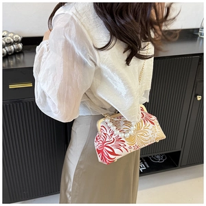 Detail of embroidered floral shell bag with large pearl handle and metal chain strap