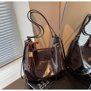 Detail of dark brown glossy PU leather tote bag with tassels and magnetic flap closure