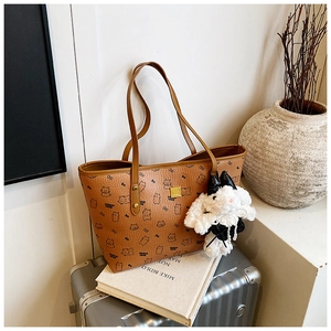 Close-up of brown printed tote bag with cartoon pattern and white plush bunny charm