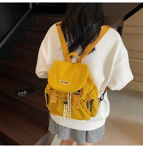Close-up of bright yellow nylon backpack with drawstring closure and buckle details