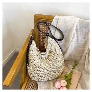 Detail of straw shoulder bag with brown leather strap on a rustic chair