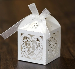 Détail d'une boîte à dragées blanche découpée au laser avec texte LOVE et ruban blanc
