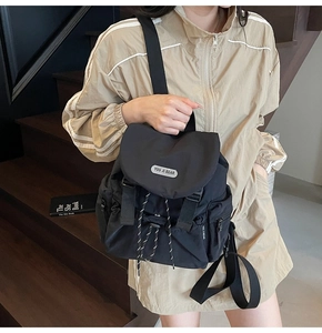 Detailed close-up of a black nylon backpack with a drawstring closure and buckle flap