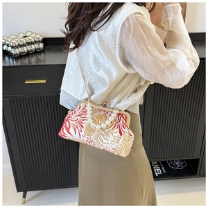 Detail of floral embroidery on a retro shell bag with pearl handle and gold chain