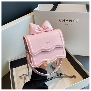 Detail of light pink mini bag with bow accent, wavy edge, and silver KCMK logo chain