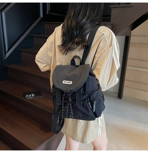 Detail of black waterproof nylon backpack featuring flap closure and branded brand label