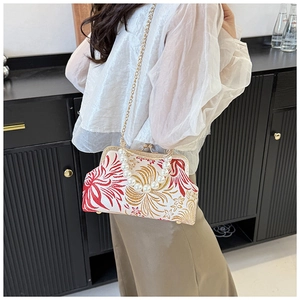 Close-up of vintage floral embroidery crossbody bag with large pearl handle and gold chain