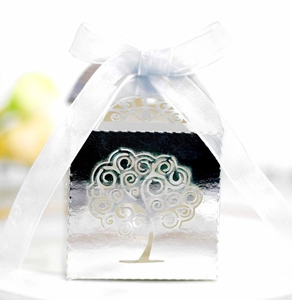 Detail of silver laser-cut candy box featuring tree of life pattern and white ribbon