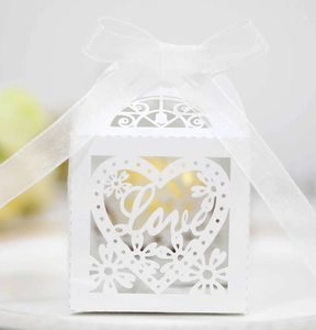 Macro detail of white laser-cut wedding favor box featuring LOVE heart and ribbon